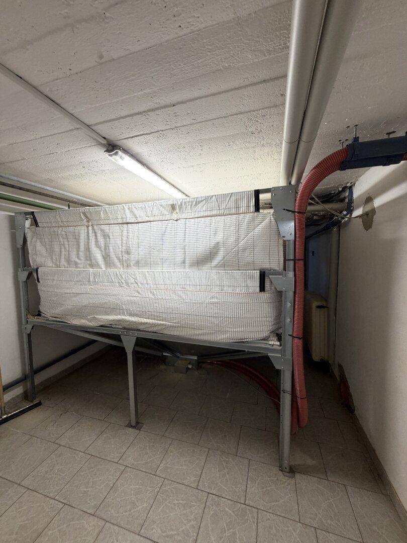 Lagerraum im Keller mit Pelletlager oder ähnlicher Schüttgutlagerung für Heizmaterial.
