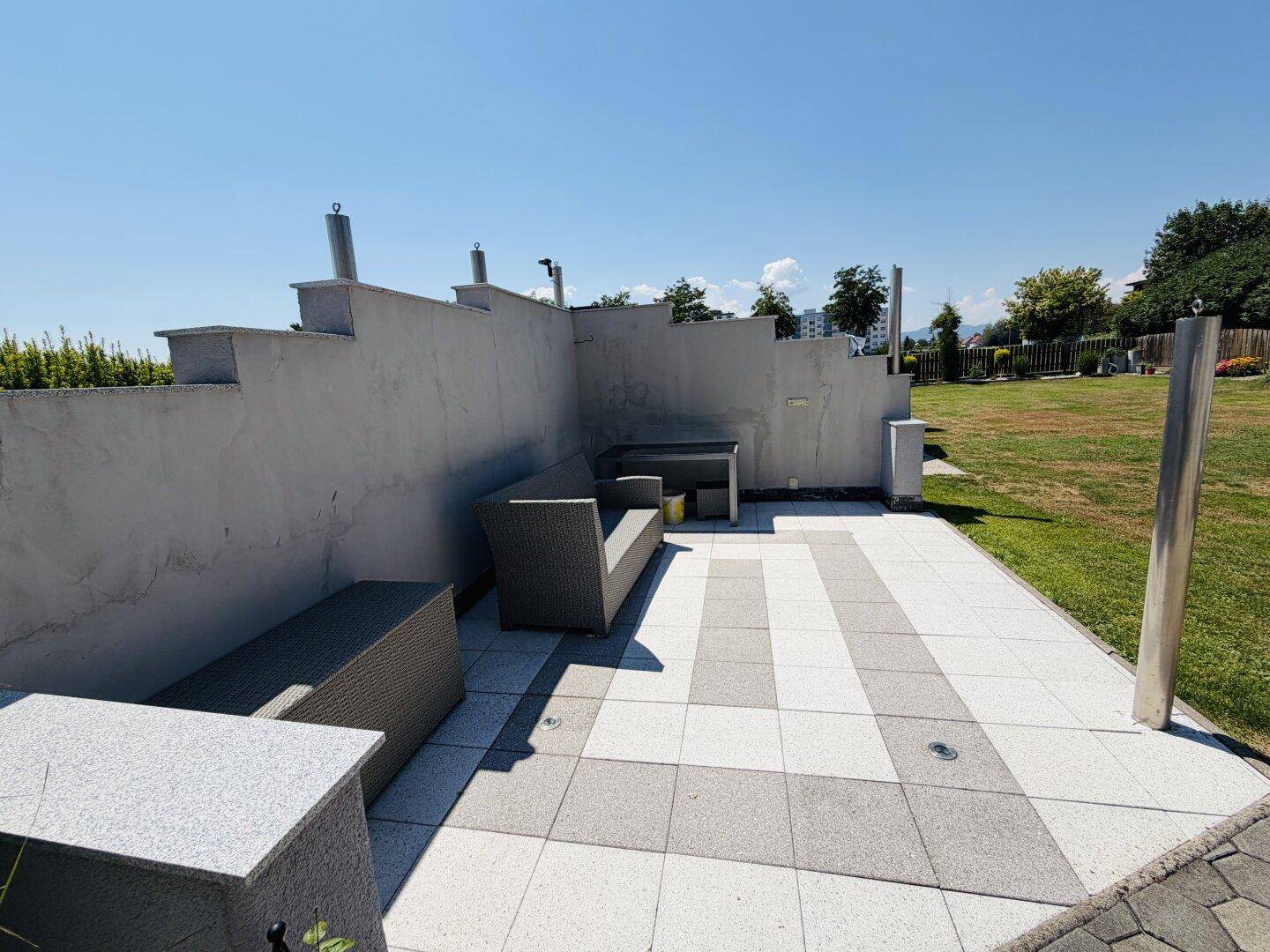 Stilvolle Terrasse mit modernen Outdoor-Möbeln und einer Kombination aus hellen und dunklen Fliesen.