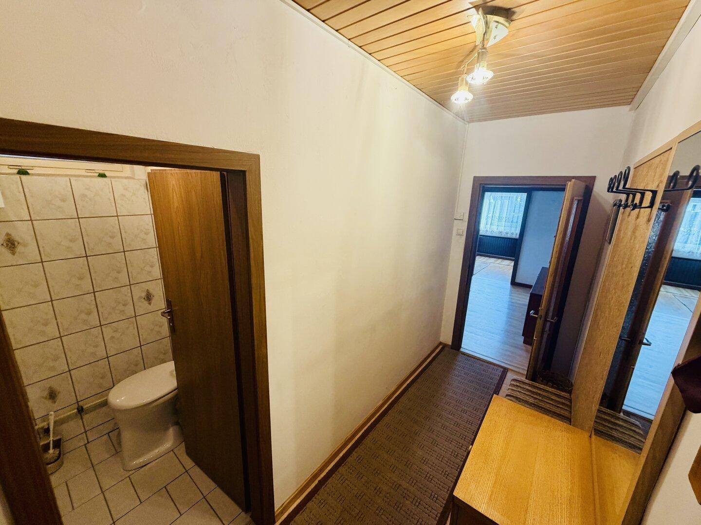 Schmaler Flur mit Zugang zu verschiedenen Räumen, inklusive einer Toilette.