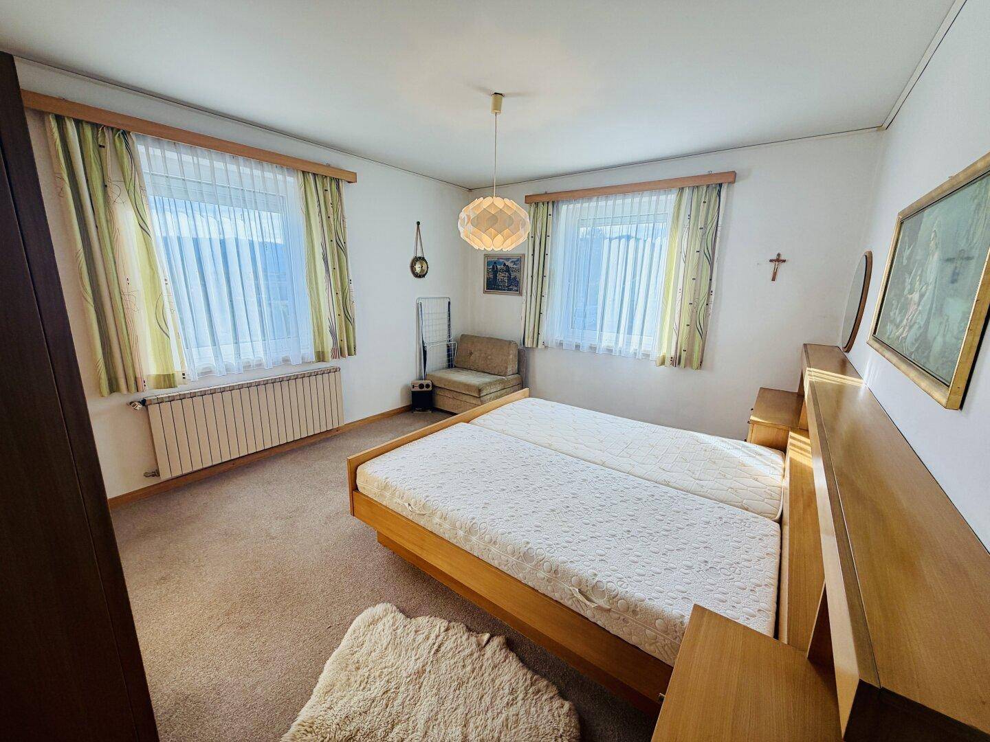 Geräumiges Schlafzimmer mit Doppelbett, Teppichboden und zwei Fenstern für viel Licht.