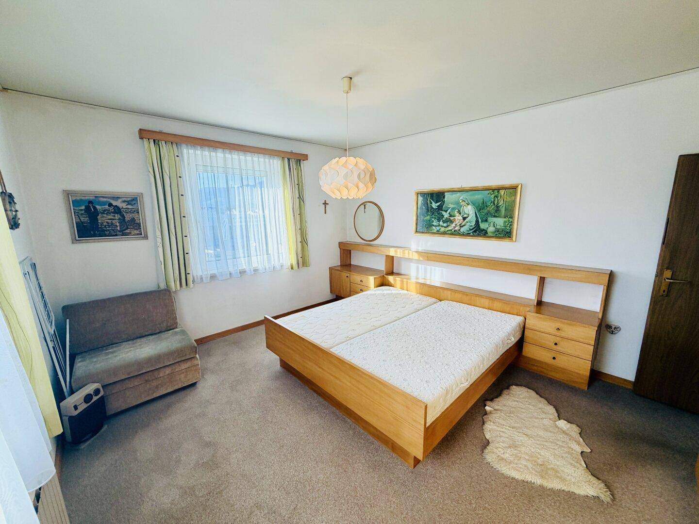 Helles Schlafzimmer mit Doppelbett, Teppichboden und Nachttischen, funktional eingerichtet.