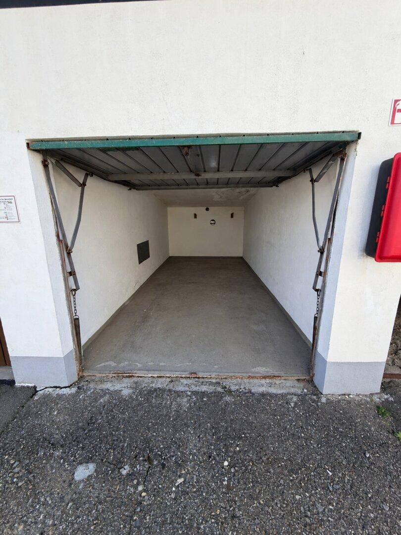 Leere Einzelgarage mit offenem Tor und Betonboden, bereit zur Nutzung.