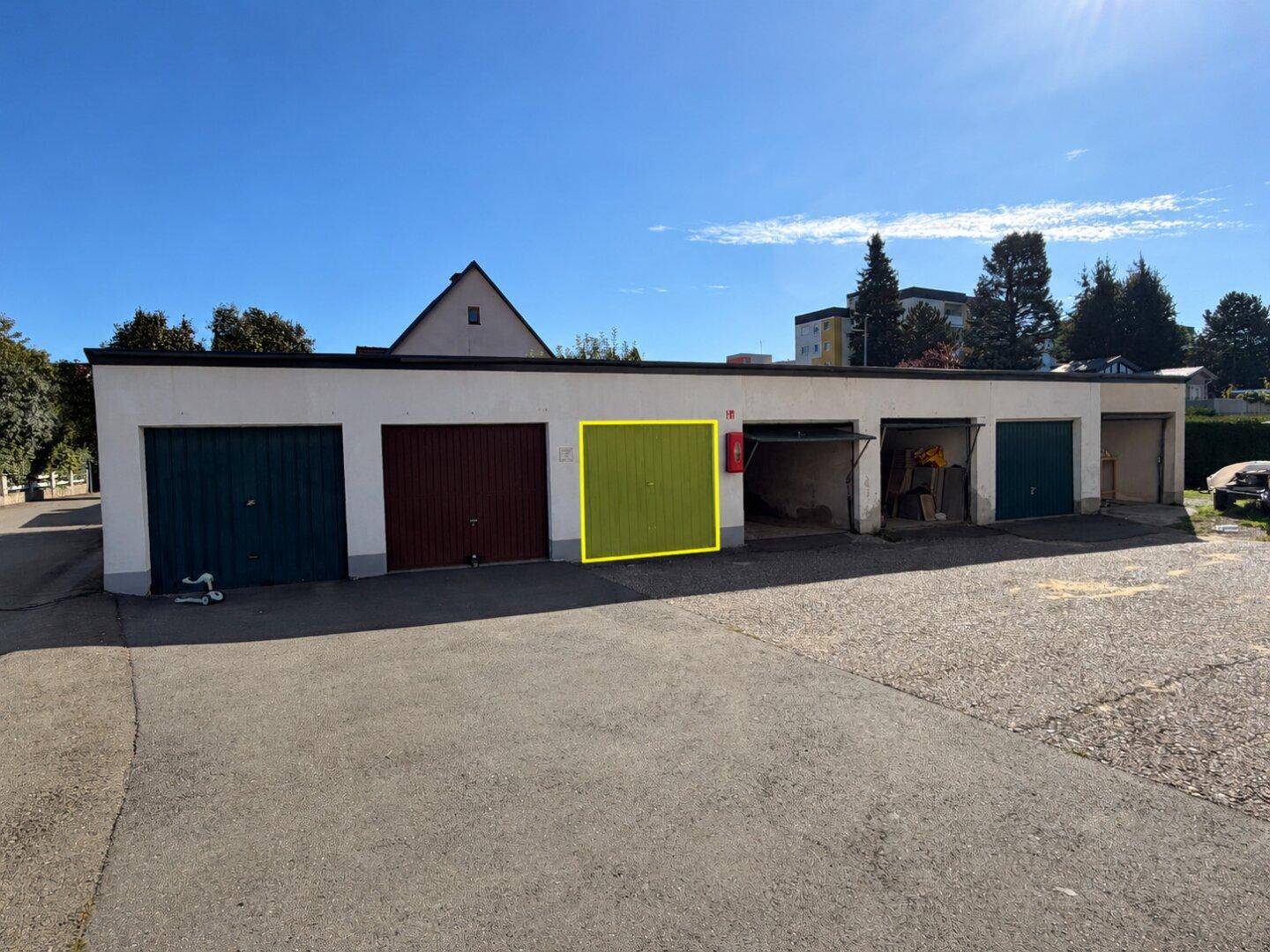 Reihe von Garagen mit hervorgehobener Einzelgarage unter blauem Himmel.