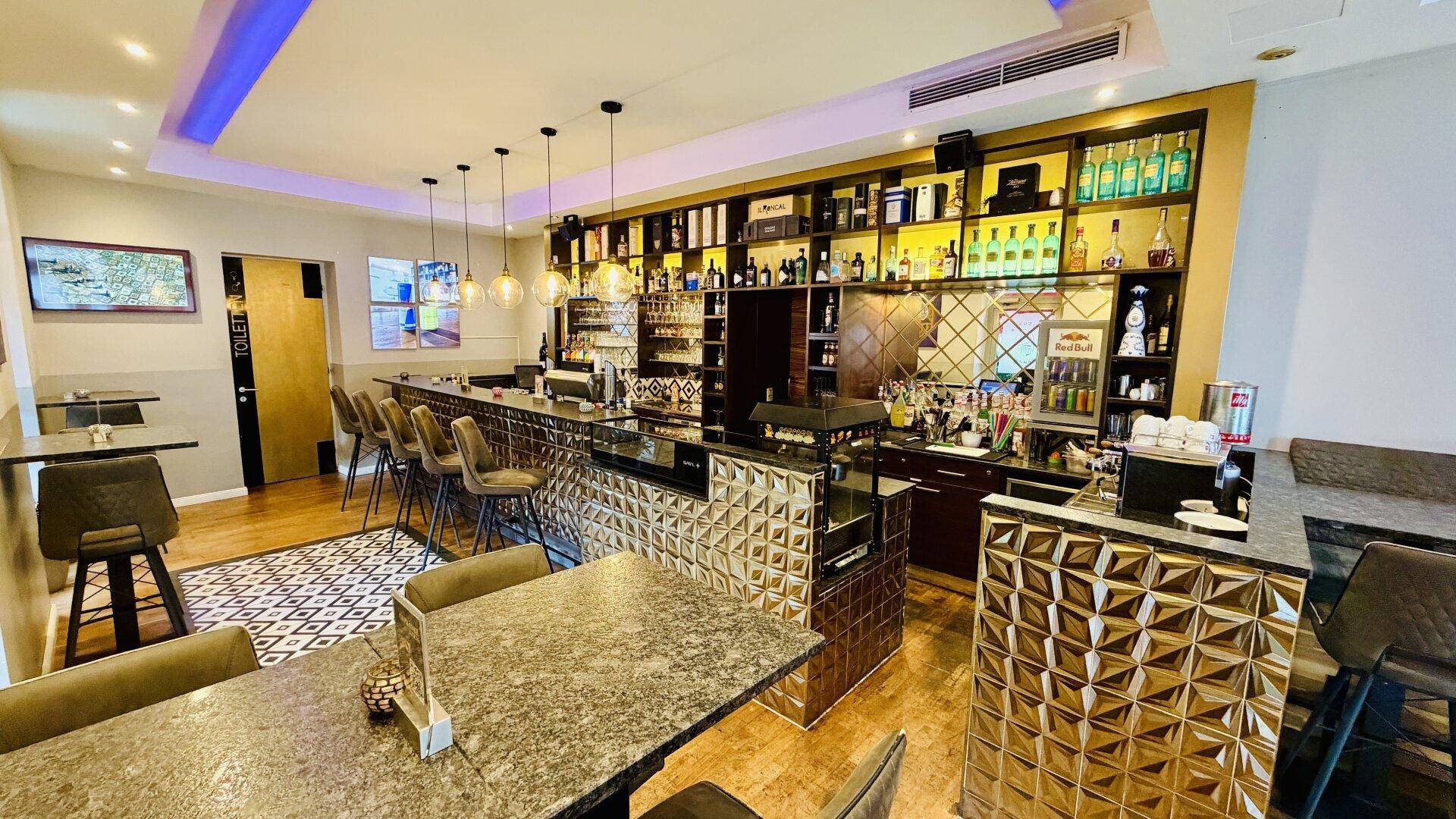 Bar- und Sitzbereich eines Cafés mit Zugang zu den Toiletten und stilvoller Einrichtung.