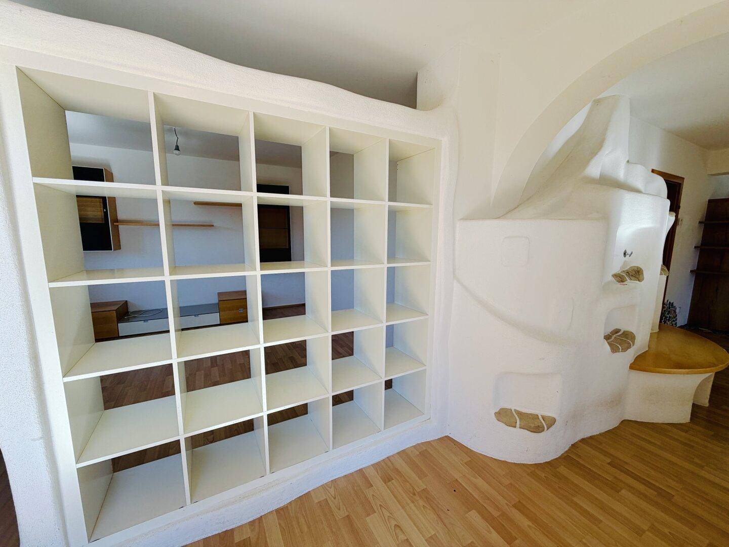 Geräumiger Innenraum mit integriertem weißen Regal und geschwungener Wandgestaltung, ideal für Stauraum.