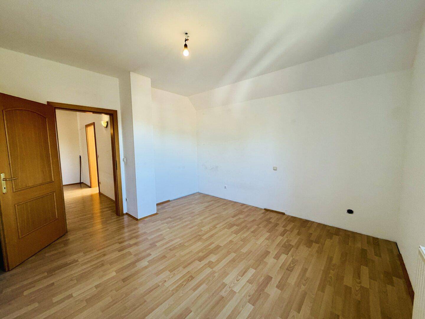 Helles Schlafzimmer mit Laminatboden und Holztür, bietet eine ruhige und private Rückzugsmöglichkeit.