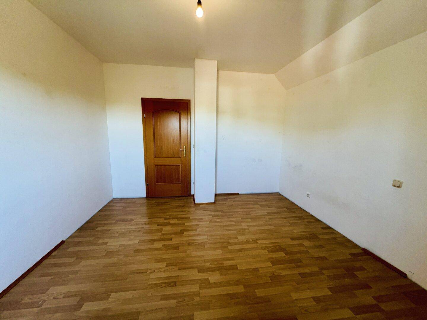 Leeres Schlafzimmer mit Laminatboden und weiß gestrichenen Wänden, bereit für neue Bewohner.