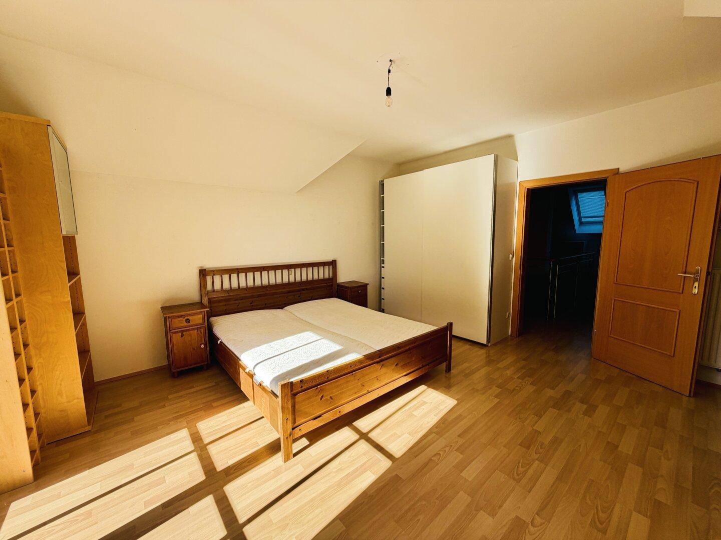 Schlafzimmer mit Holzbett und integriertem Kleiderschrank, bietet praktischen Stauraum.