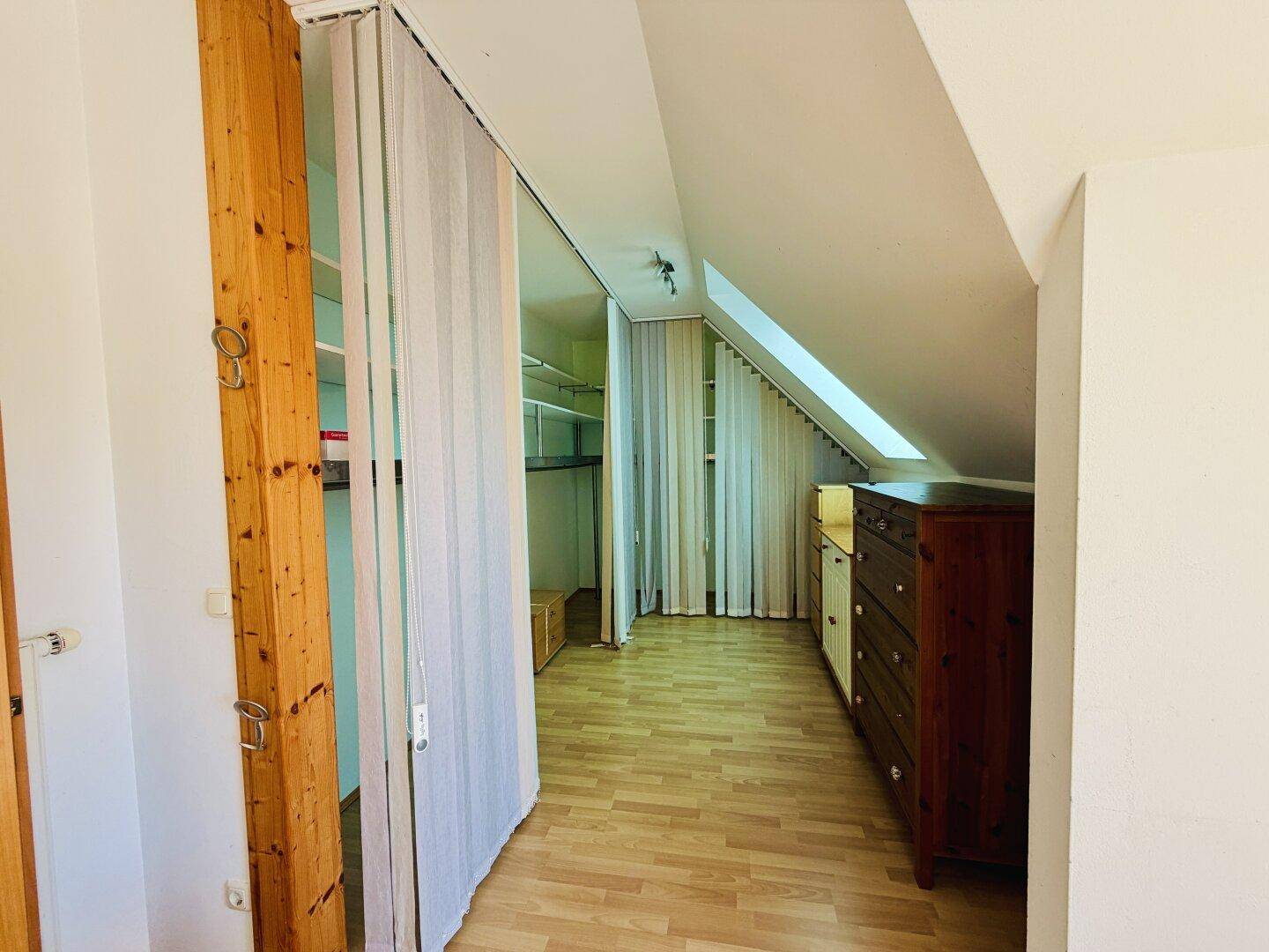 Praktischer begehbarer Kleiderschrank mit Regalen und Vorhängen, bietet viel Stauraum unter der Dachschräge.