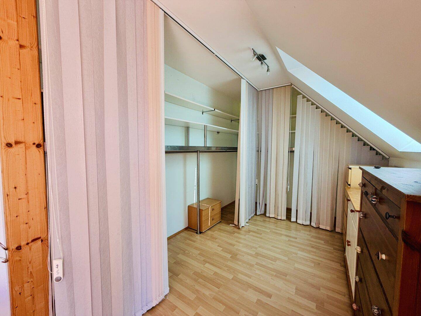 Geräumiger begehbarer Kleiderschrank mit offenen Regalen und Kleiderstange, gut organisiert.