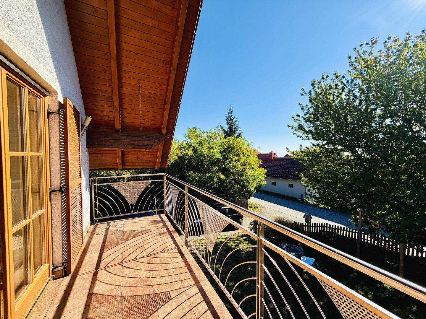 Balkon mit Metallgeländer und Holzdach, bietet eine weite Aussicht auf die Umgebung.