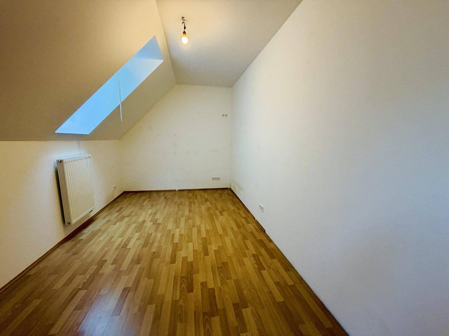 Helles Dachzimmer mit Dachfenster, Laminatboden und Heizkörper, vielseitig nutzbar.