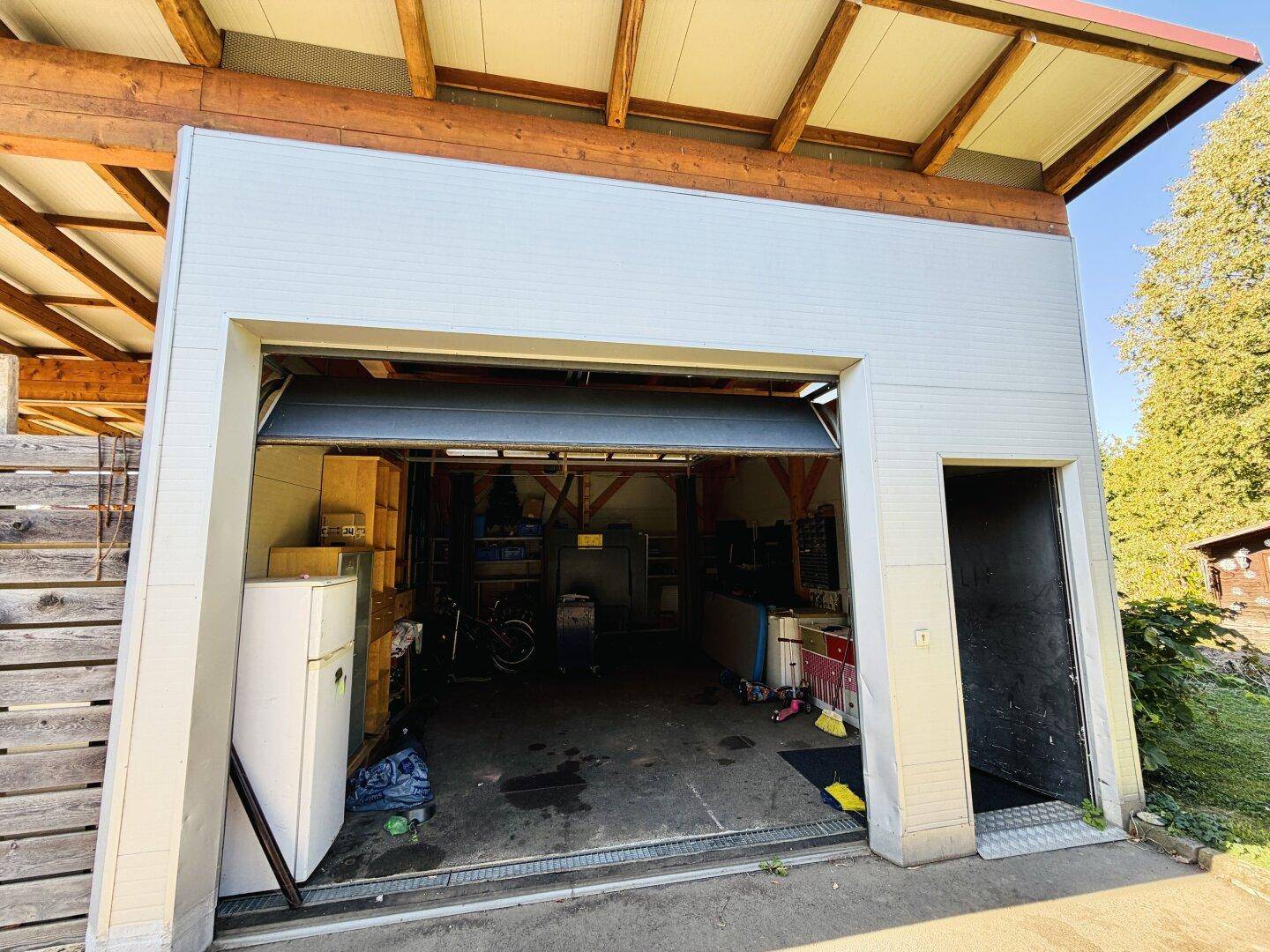 Innenansicht der Garage mit Stauraum, Kühlschrank und verschiedenen Gegenständen.