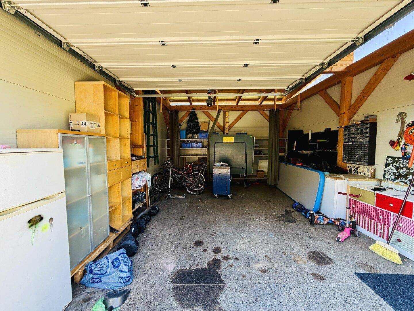 Geräumige Garage mit Regalen, Fahrrad und vielseitigem Stauraum für Werkzeuge und Geräte.