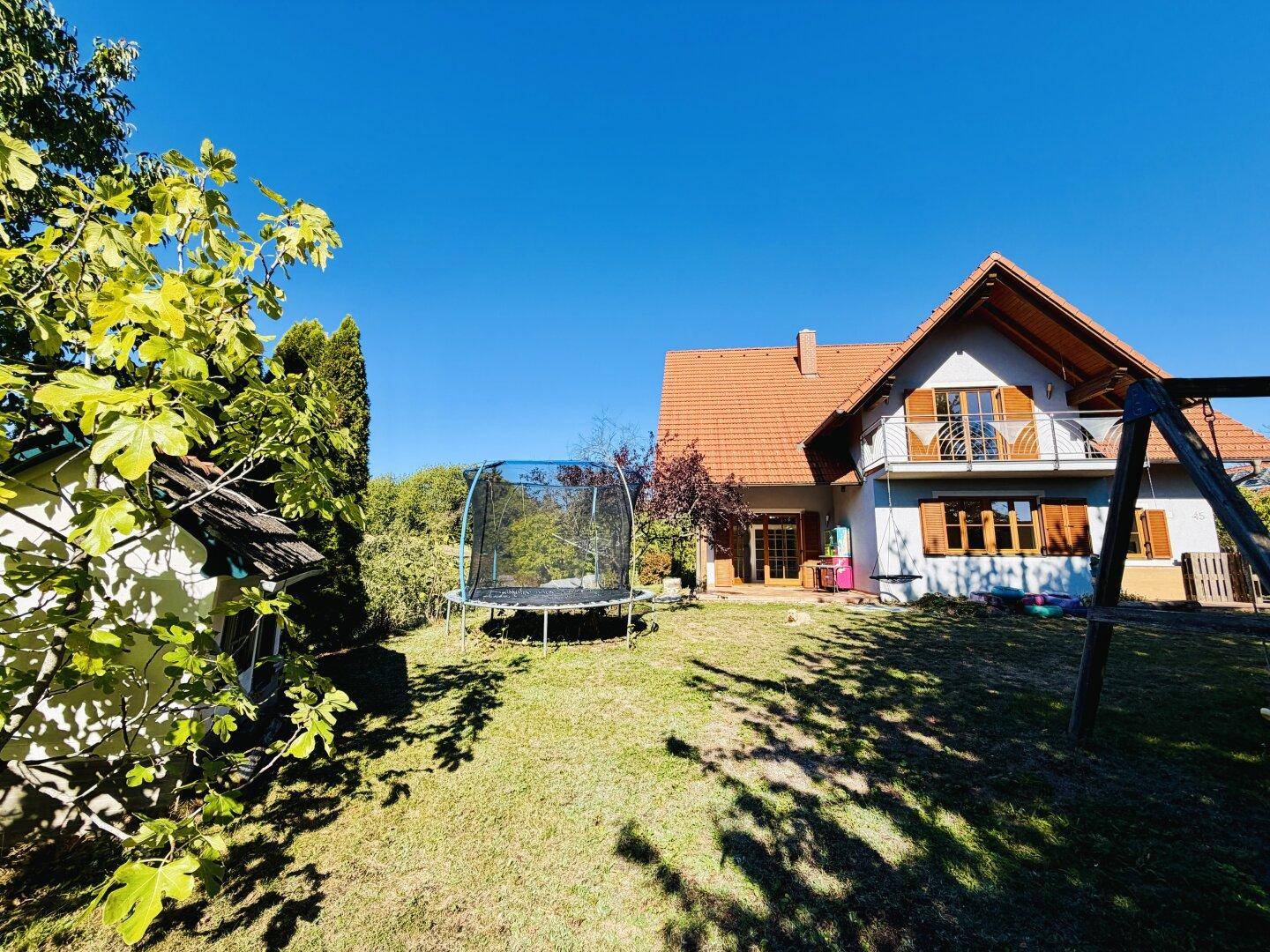 Geräumiger Garten mit Trampolin und Spielhaus, ideal für Familienaktivitäten im Freien.