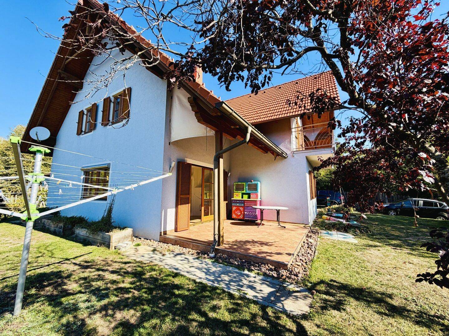 Gemütliche Terrasse mit Fliesenboden, bunten Möbeln und Zugang zum Garten.