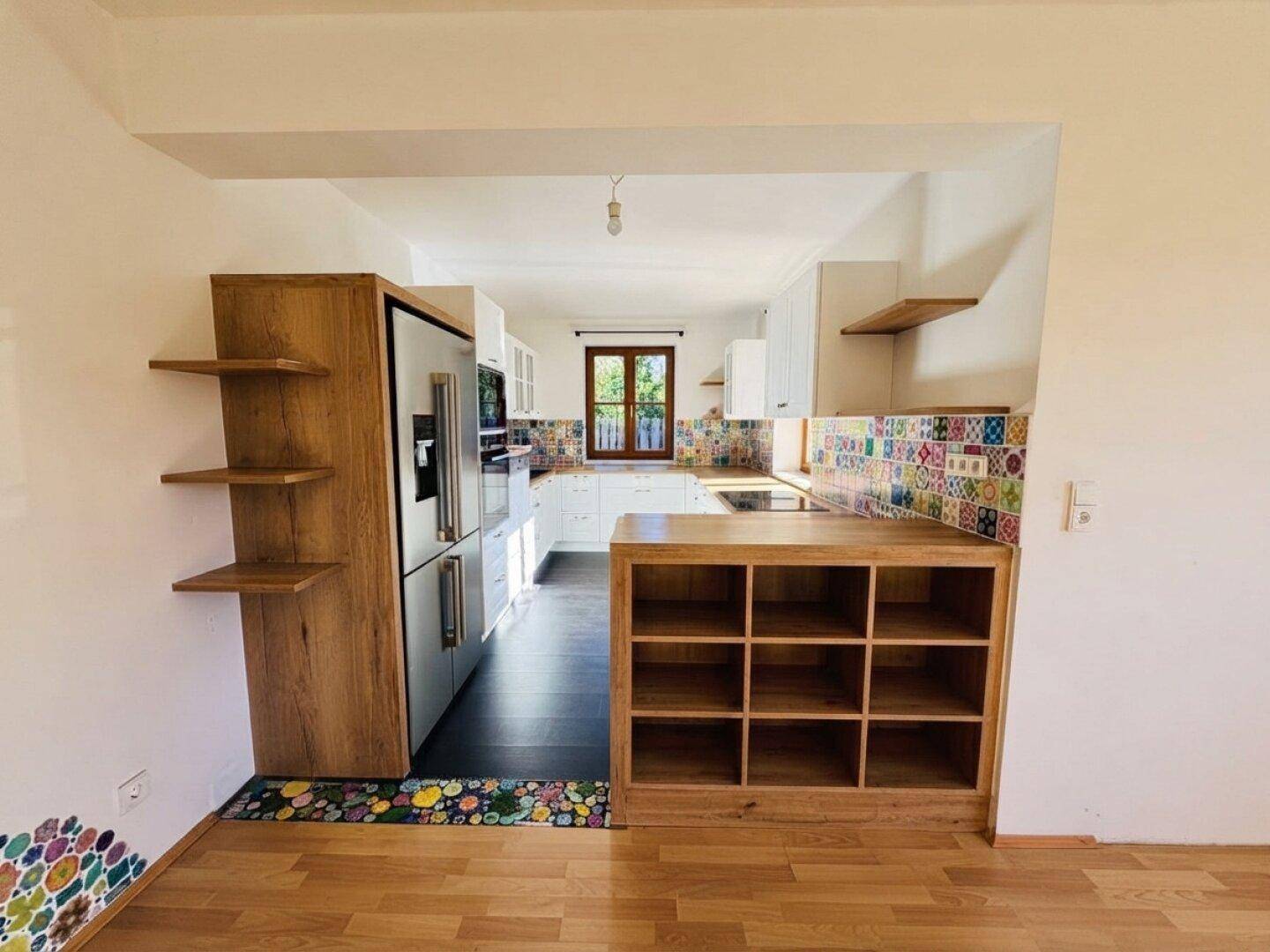 Offener Wohnbereich mit Blick auf die Küche, gekennzeichnet durch Holzboden und moderne Einrichtung.