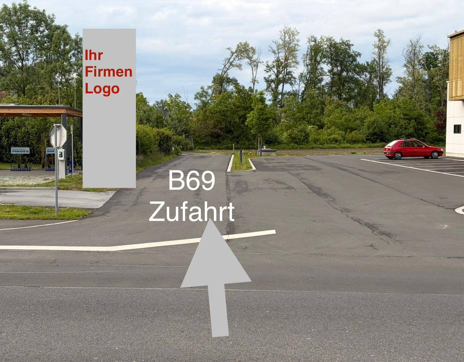 Zufahrt zum Grundstück von der B69 mit asphaltiertem Parkplatz und Platz für ein Firmenlogo.