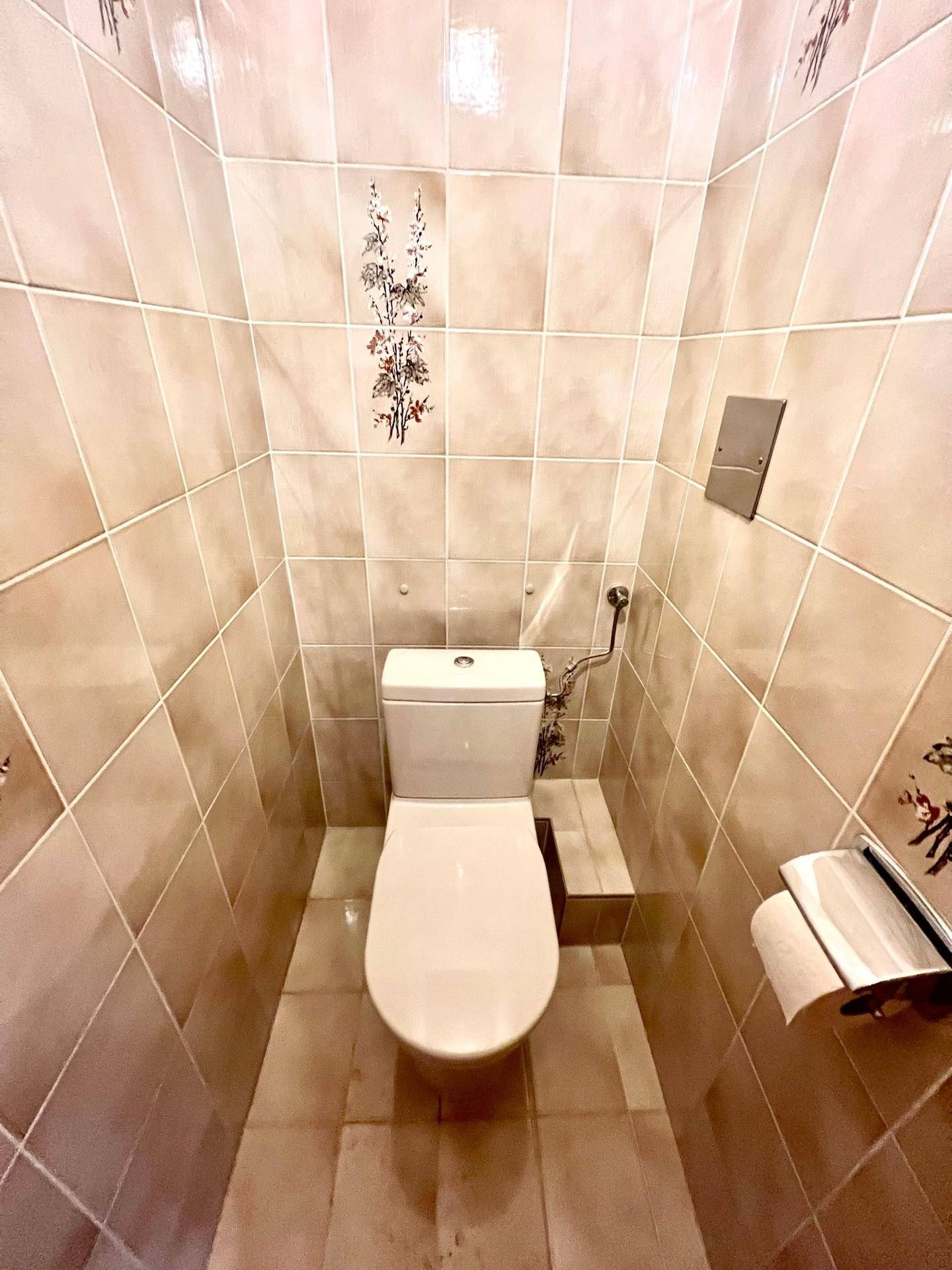 Separate Toilette mit beigefarbenen Fliesen und einfacher Ausstattung, die funktional und sauber ist.