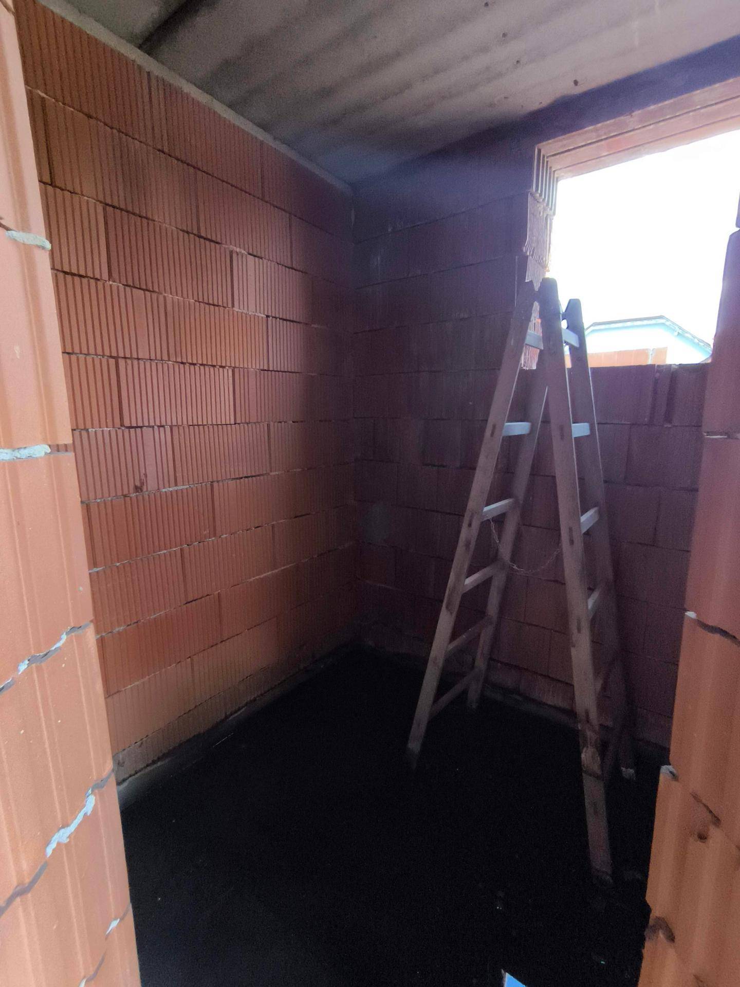Kleiner, unfertiger Raum mit Ziegelwänden und einer Fensteröffnung, ideal als Abstellraum.