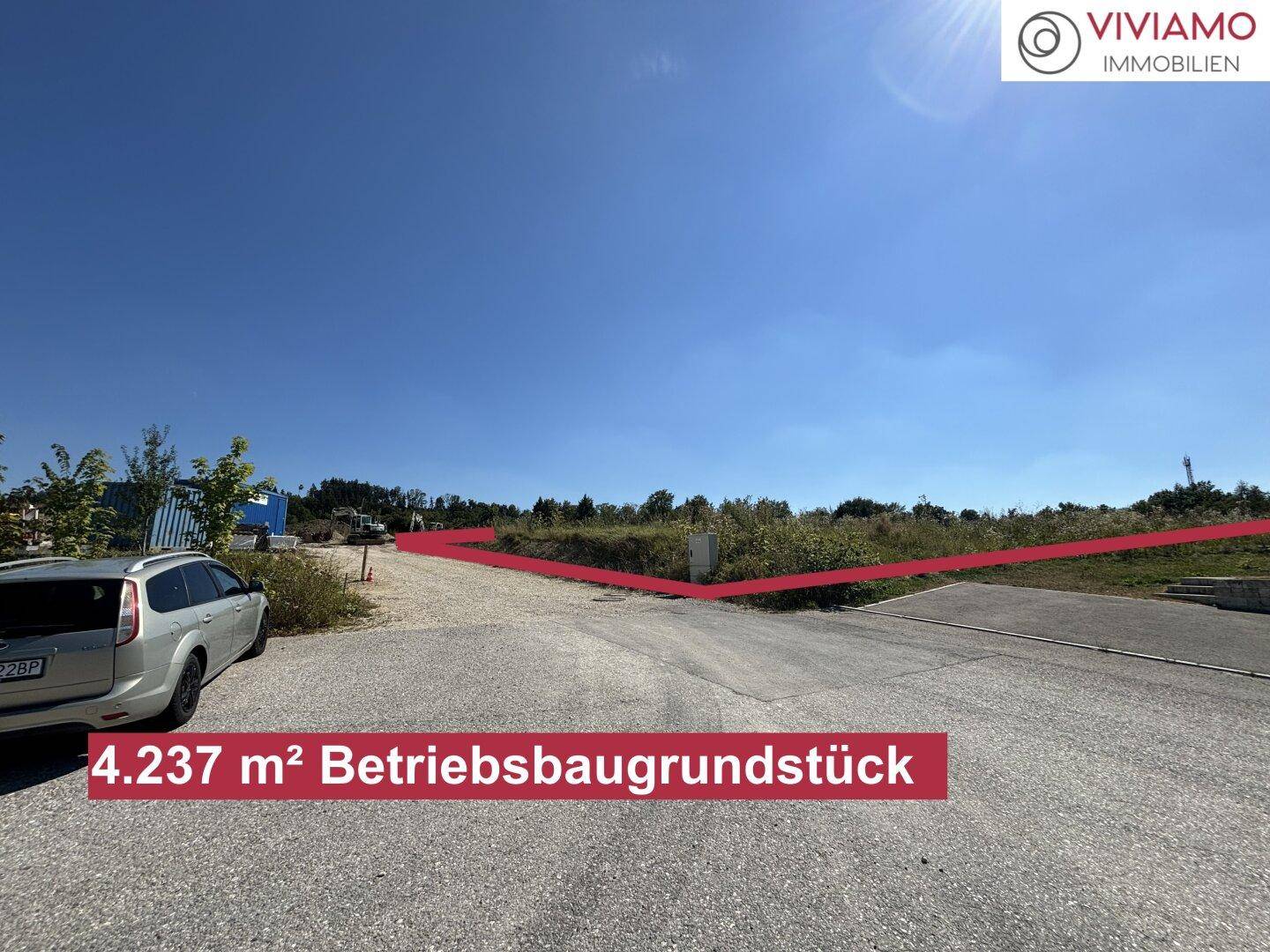 Zufahrtsbereich zum Betriebsbaugrundstück mit geparktem Auto und Blick auf die angrenzende, unbebaute Fläche.
