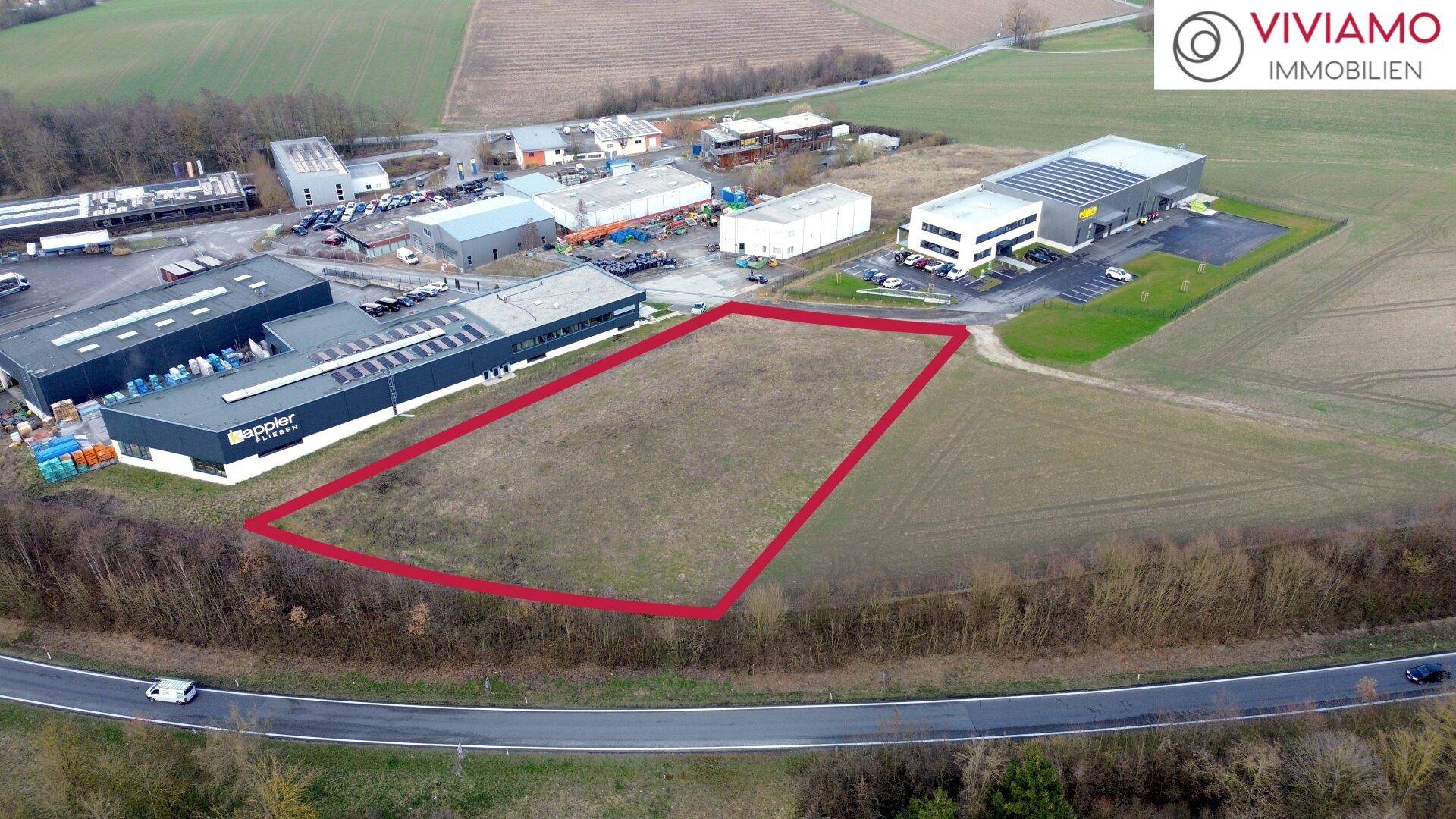 Übersichtliche Luftaufnahme des Baugrundstücks, umgeben von weiteren Gewerbeimmobilien und einer Zufahrtsstraße.