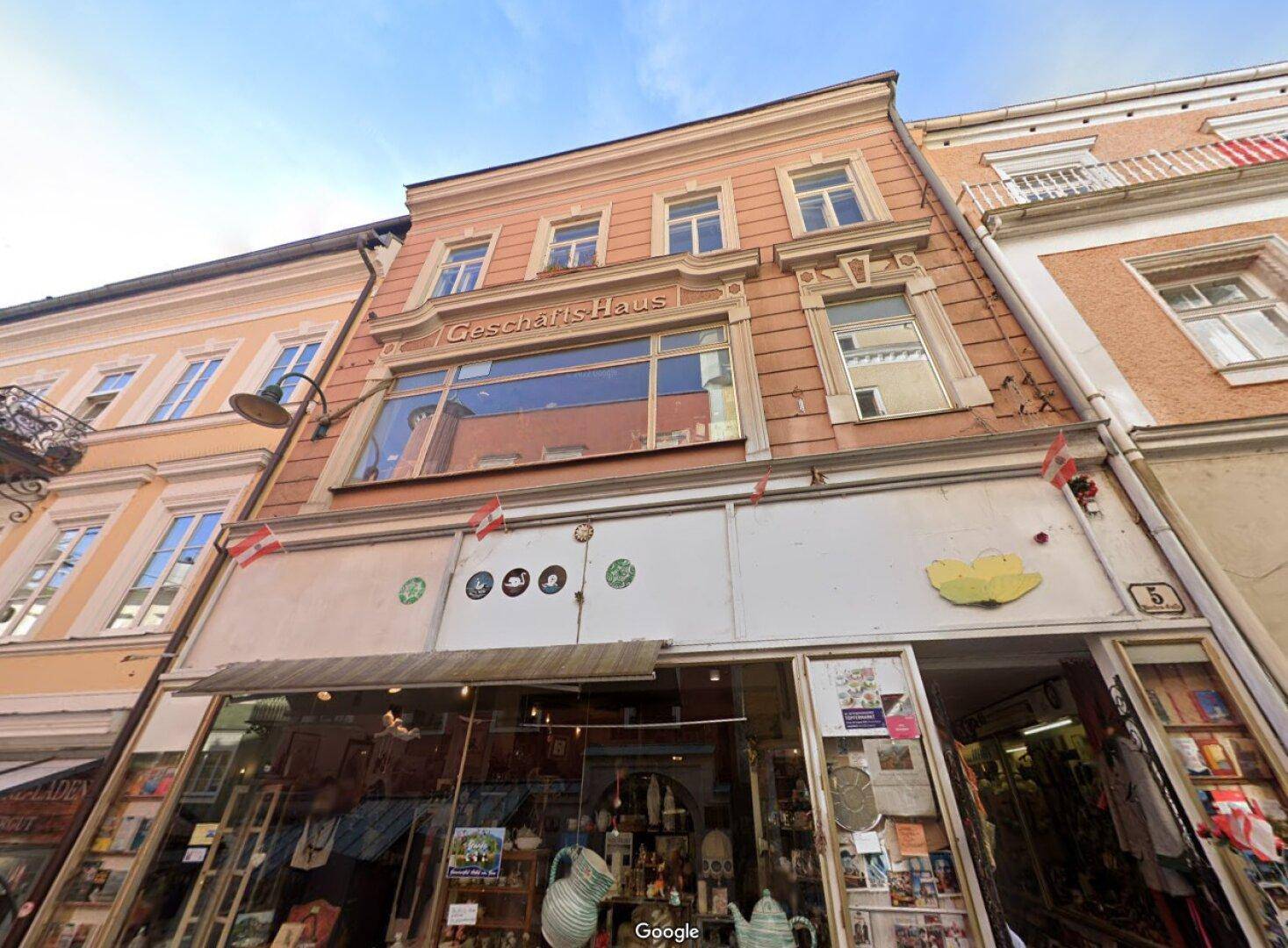 Historisches Geschäftsgebäude mit traditioneller Fassade und Schaufenstern im Erdgeschoss.