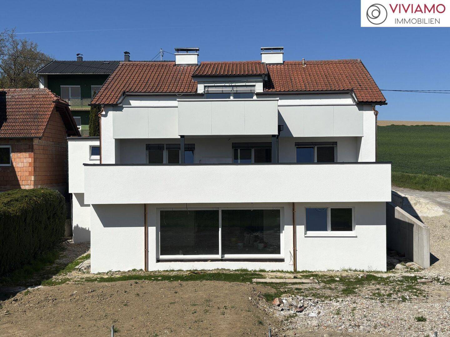 Vorderansicht der modernen Doppelhaushälfte mit Balkonen und großen Fenstern.