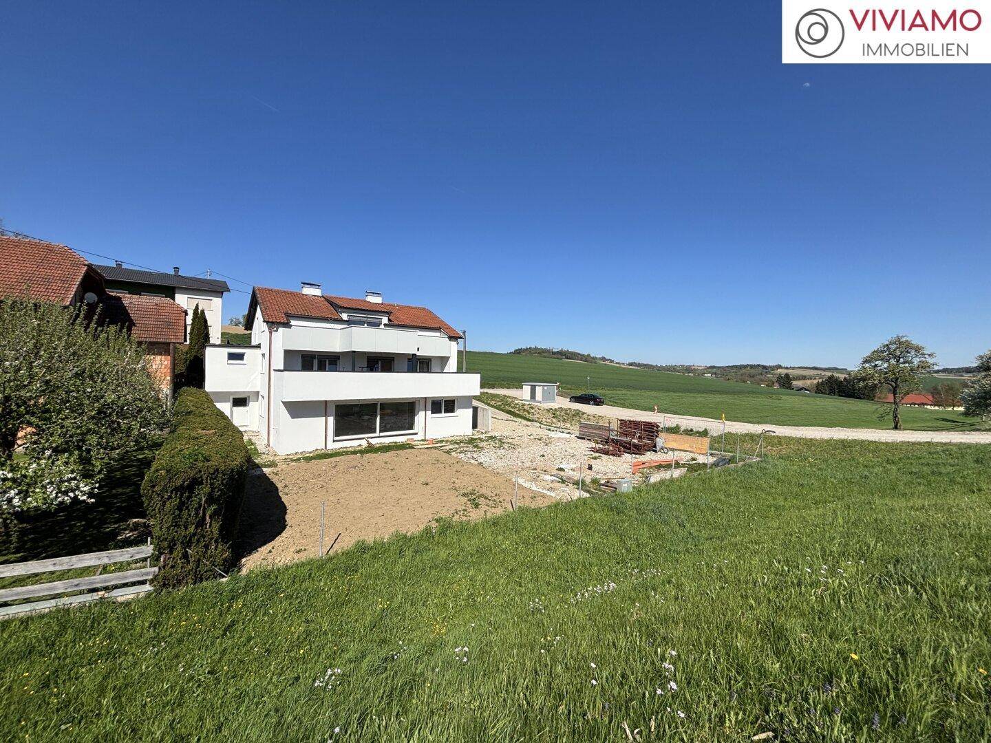 Weitläufiger Blick auf die moderne Doppelhaushälfte und die umliegende grüne Landschaft.