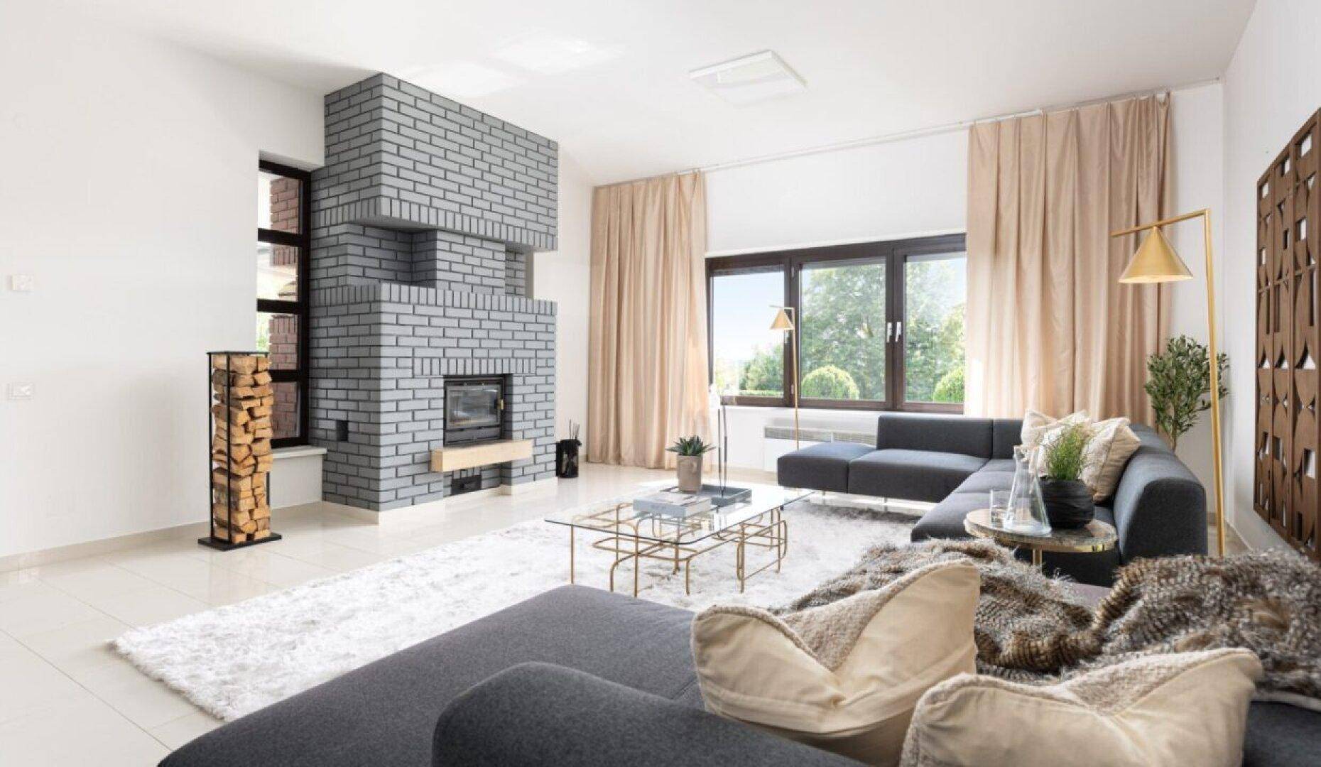 Helles Wohnzimmer mit modernem Kamin aus Ziegeln, bequemen Sofas und großen Fenstern.