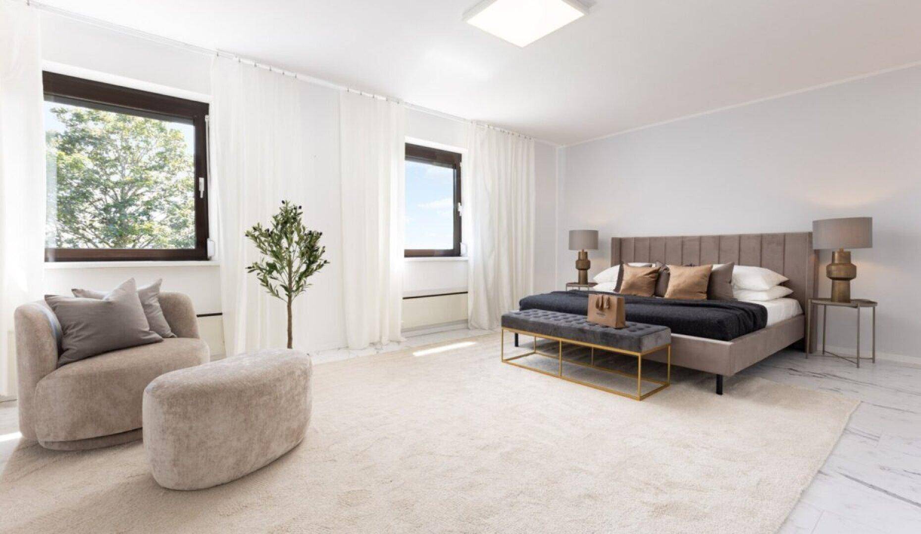 Geräumiges Schlafzimmer mit großem Bett, bequemer Sitzecke und viel natürlichem Licht.