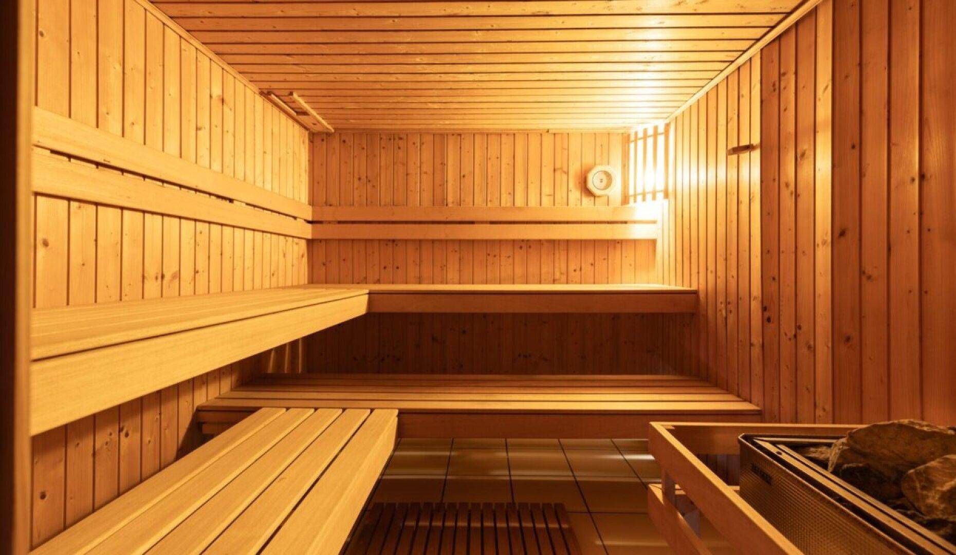 Traditionelle Holzsauna mit mehreren Bänken und klassischem Saunaofen für Entspannung.