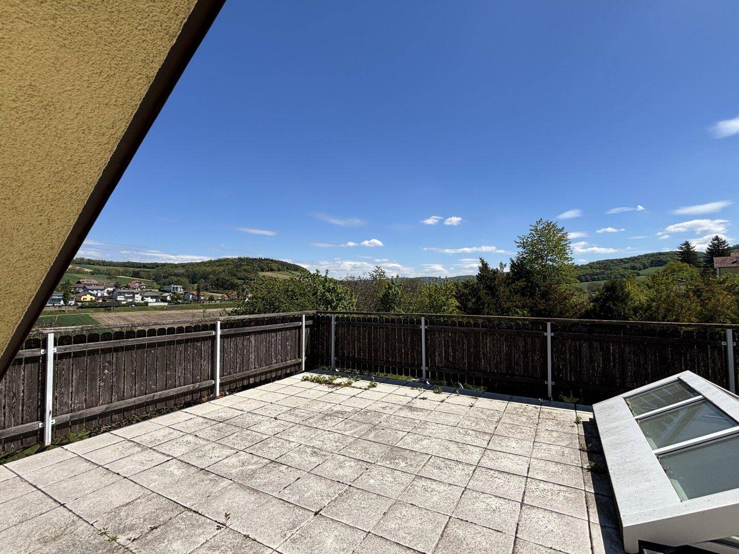 Große Dachterrasse mit weitem Blick über die grüne Landschaft und die Umgebung.