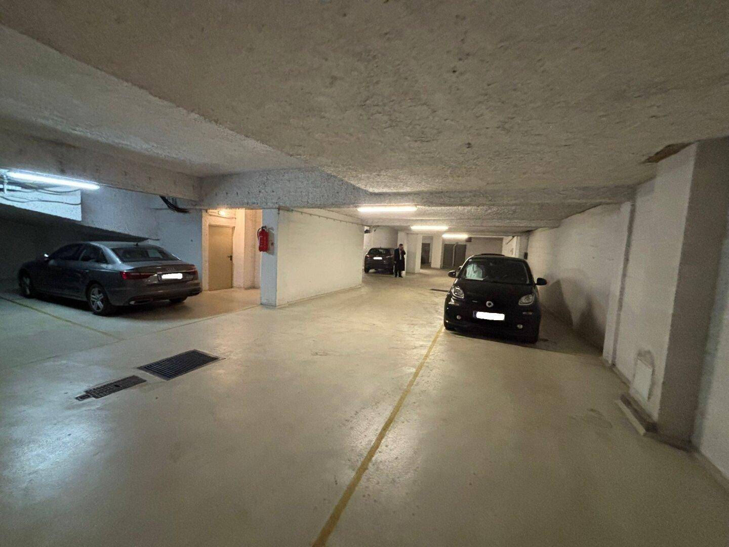 Geräumige Tiefgarage mit mehreren Fahrzeugen und Zugangstüren.