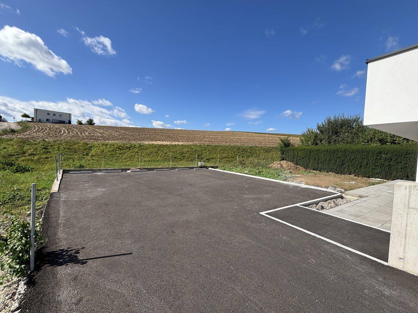 Neu angelegter Parkplatzbereich neben dem Haus mit Blick auf die umliegende Natur.