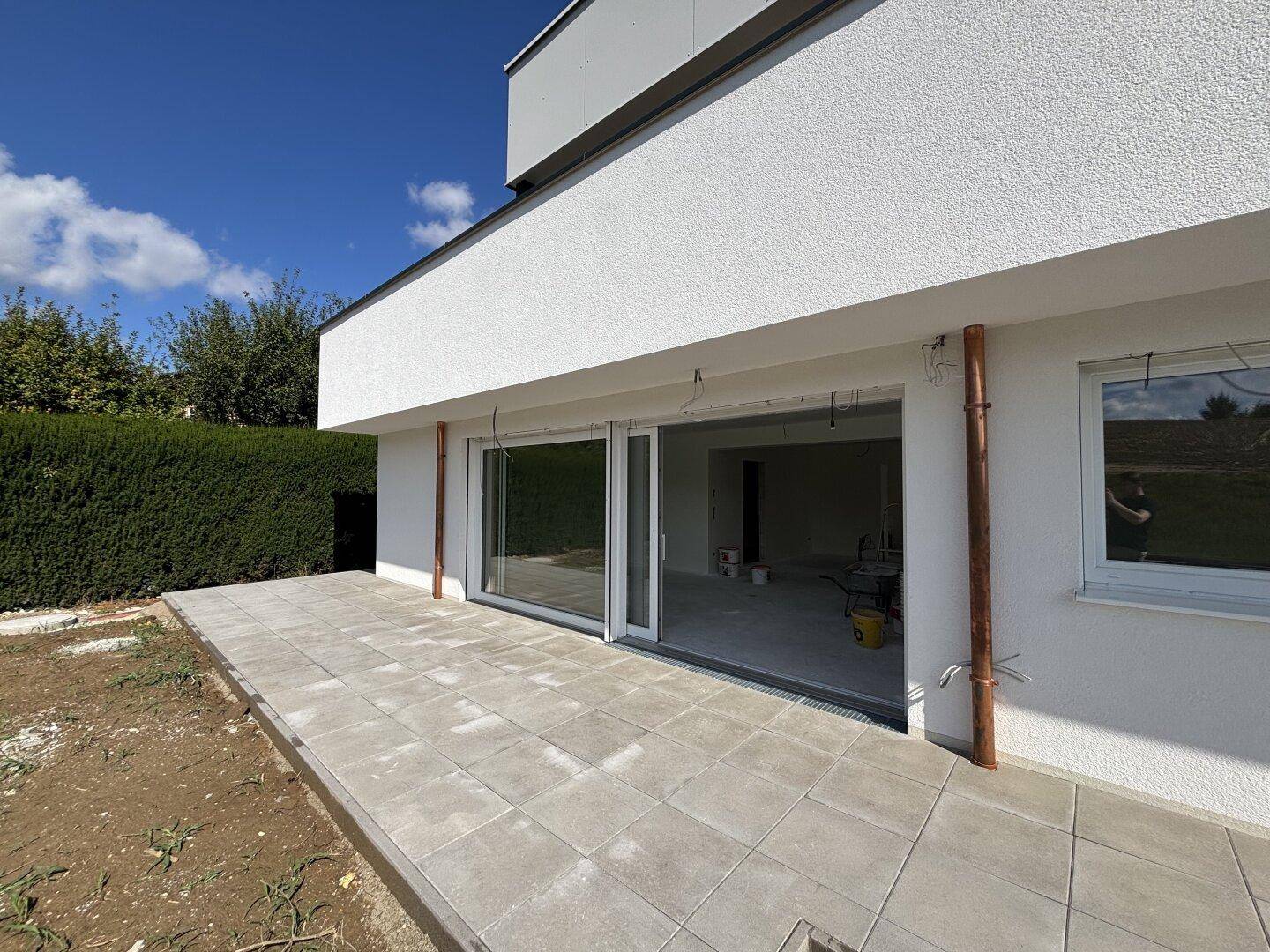 Große Glasschiebetüren öffnen sich zur Terrasse und lassen viel Licht in den Rohbau.