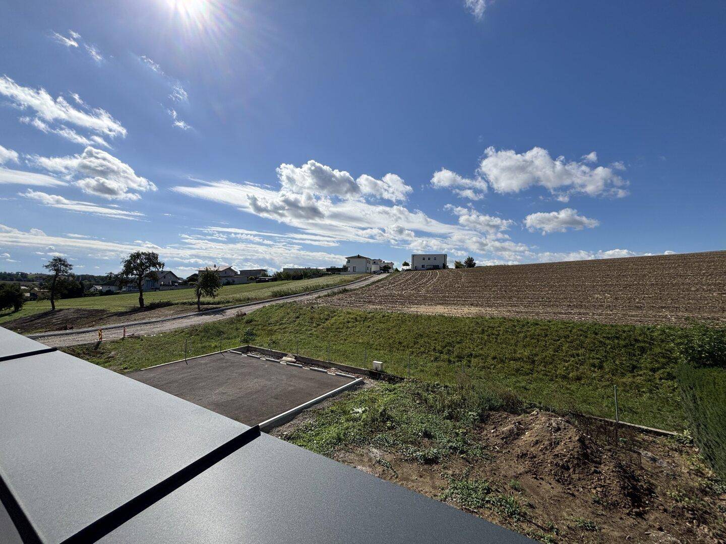 Weitläufiger Panoramablick über die grüne Hügellandschaft mit Feldern und vereinzelten Häusern.