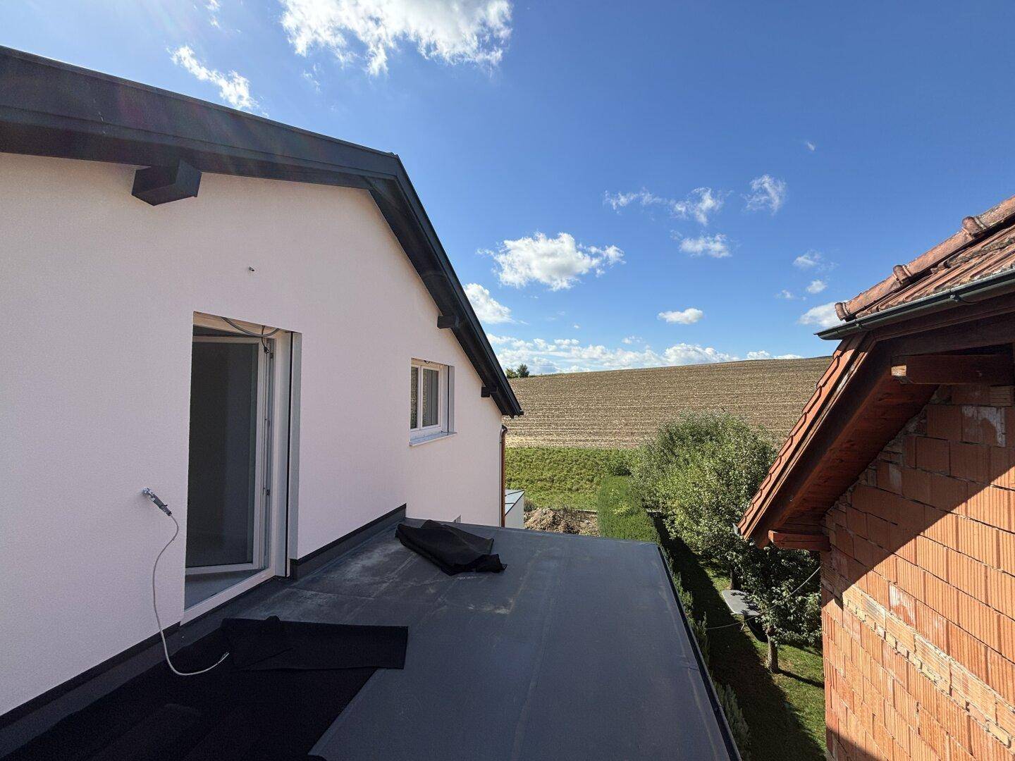 Dachterrasse mit Blick auf die umliegenden Felder und das angrenzende Gebäude.