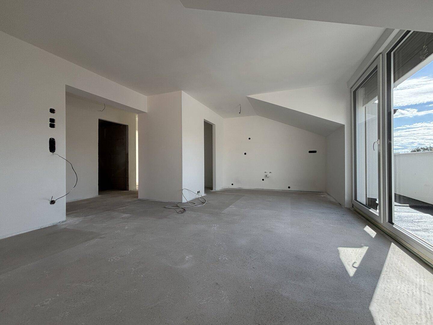 Großer, heller Raum im Dachgeschoss mit Rohbauzustand und Zugang zur Dachterrasse.
