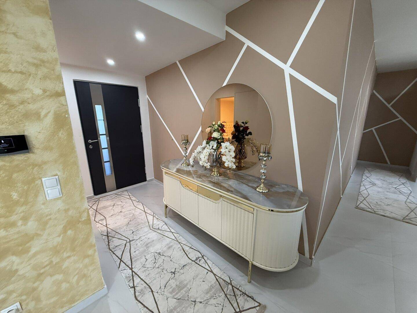 Moderner Eingangsbereich mit dekorativer Wand, Spiegel und eleganter Kommode.