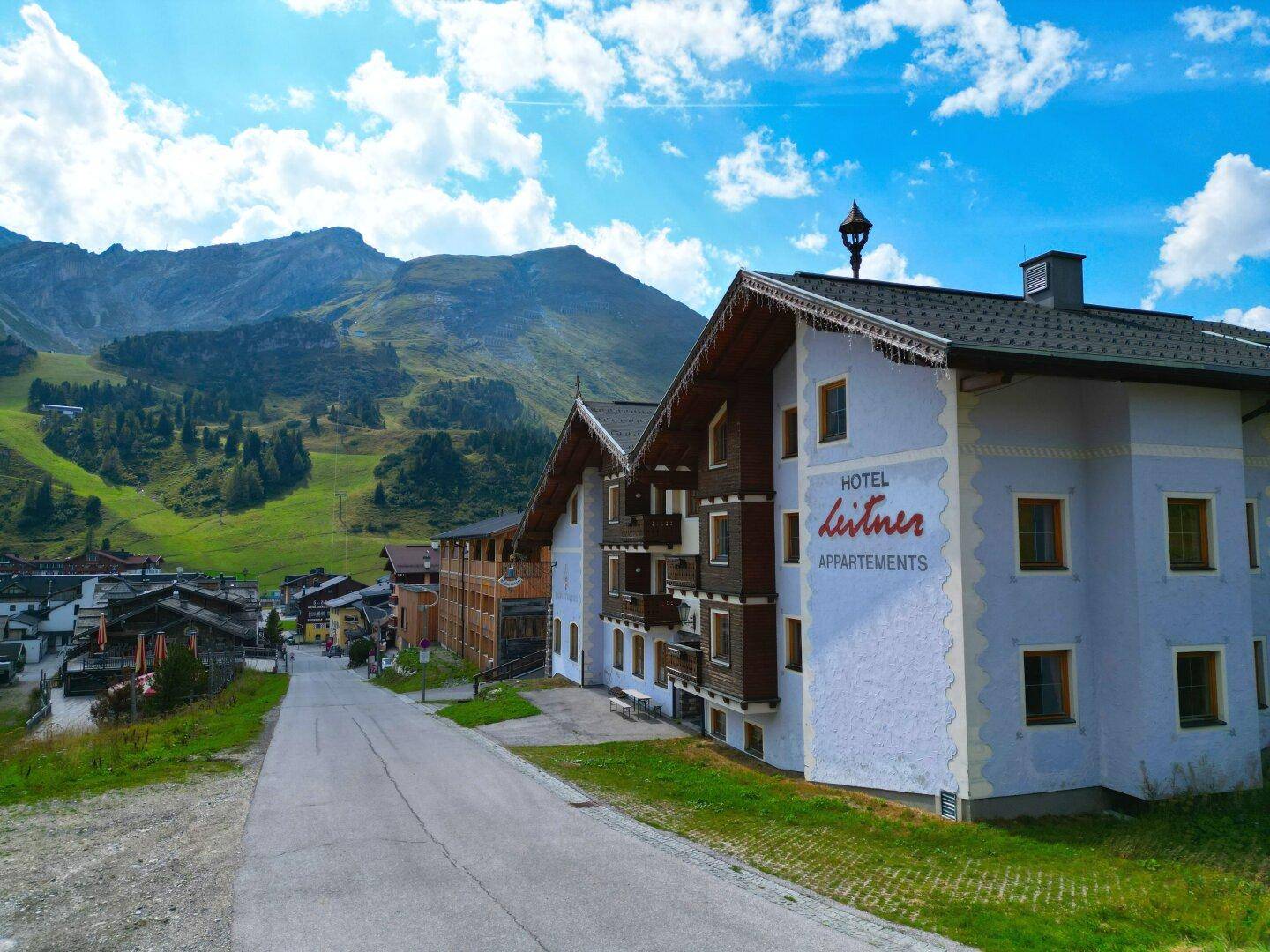 Hotelgebäude in einer Berglandschaft mit traditioneller Architektur und umliegenden Häusern.
