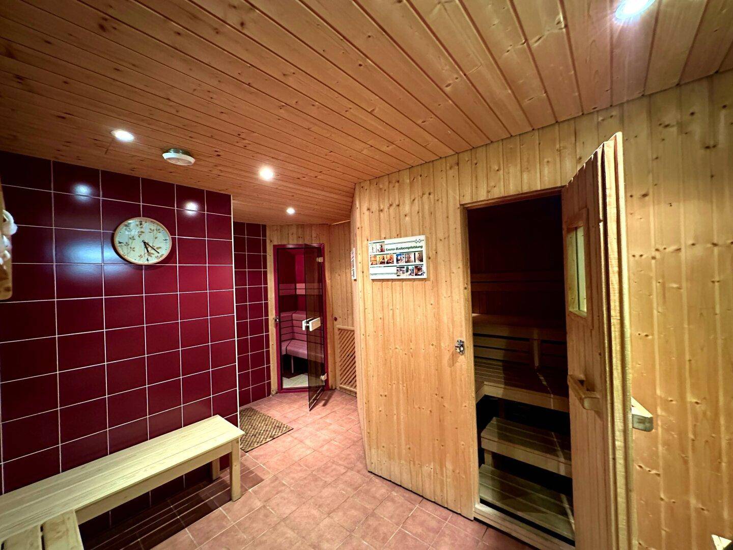 Eingangsbereich zum Wellnessbereich mit roten Fliesen und Holzbänken, führt zur Sauna.