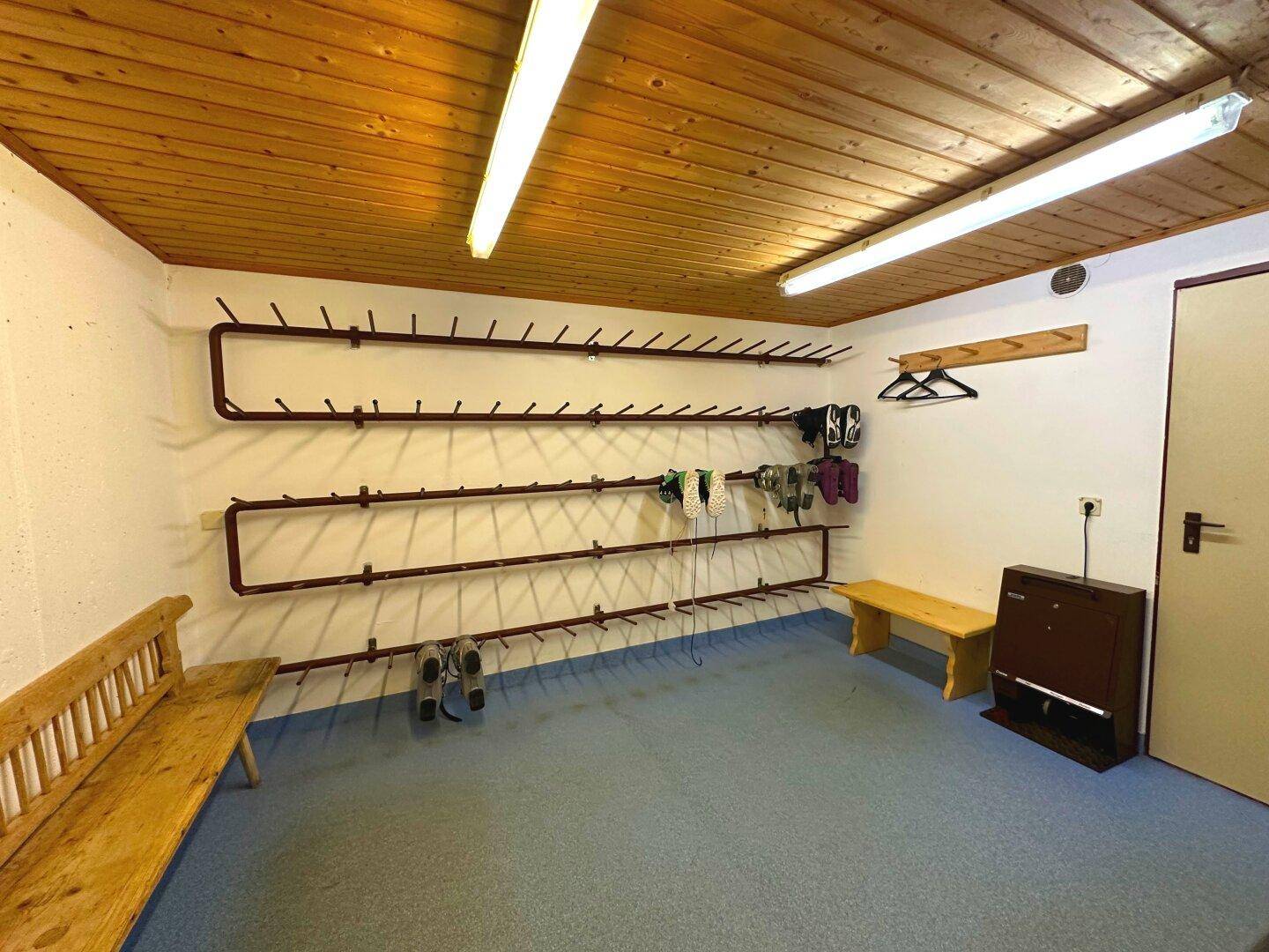 Skiraum mit Trockengestellen für Skischuhe und Bänken, ideal für Wintersportler.