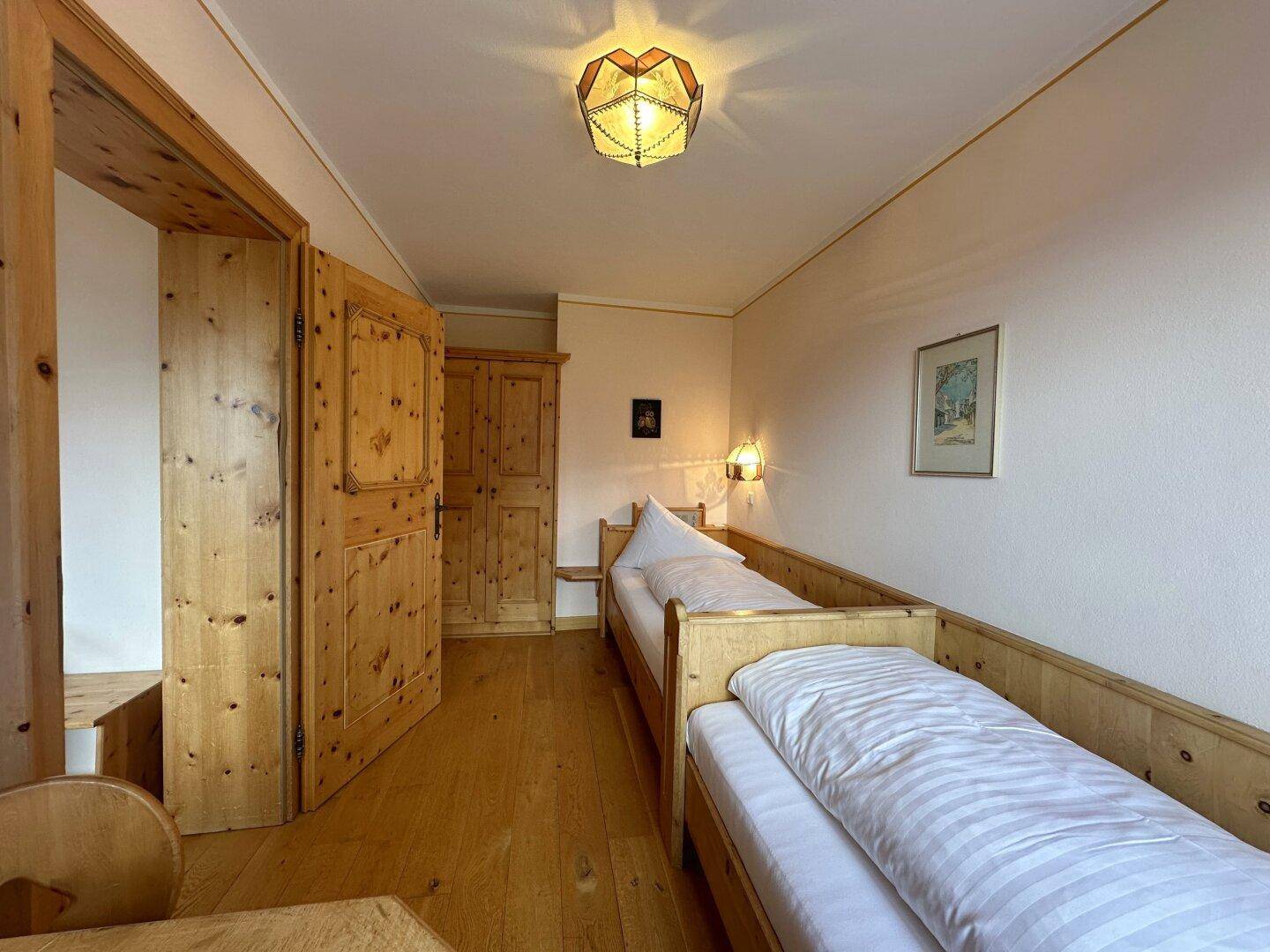 Kleines Schlafzimmer mit Einzelbetten, Holzboden und einem Holzschrank im traditionellen Stil.