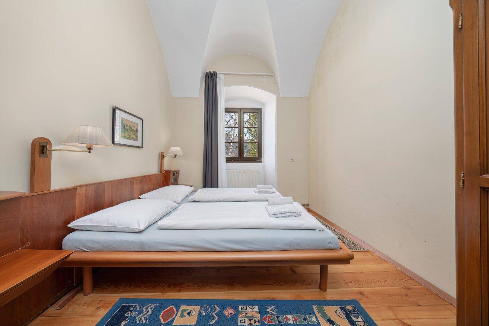 Schlafzimmer mit Holzdielenboden, Gewölbedecke und Holzbetten, bietet eine ruhige Atmosphäre.