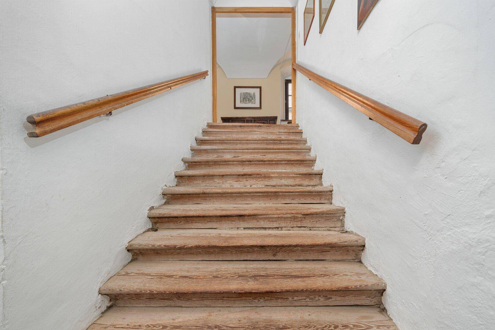 Breite Holztreppe mit robusten Stufen und Handläufen, die zu einem oberen Bereich führt.