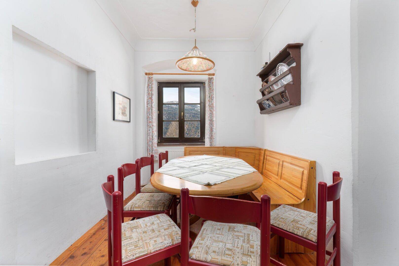 Gemütlicher Essbereich mit Holzdielenboden, Eckbank und Blick auf die verschneite Landschaft.