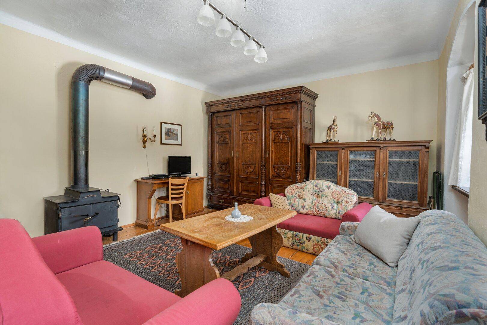 Wohnzimmer mit Holzdielenboden, Holzofen und traditionellen Möbeln, bietet eine warme Atmosphäre.