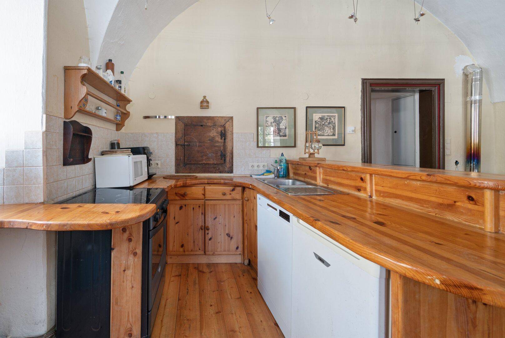 Traditionelle Küche mit Holzdielenboden, Holztheke und Einbaugeräten, bietet viel Arbeitsfläche.