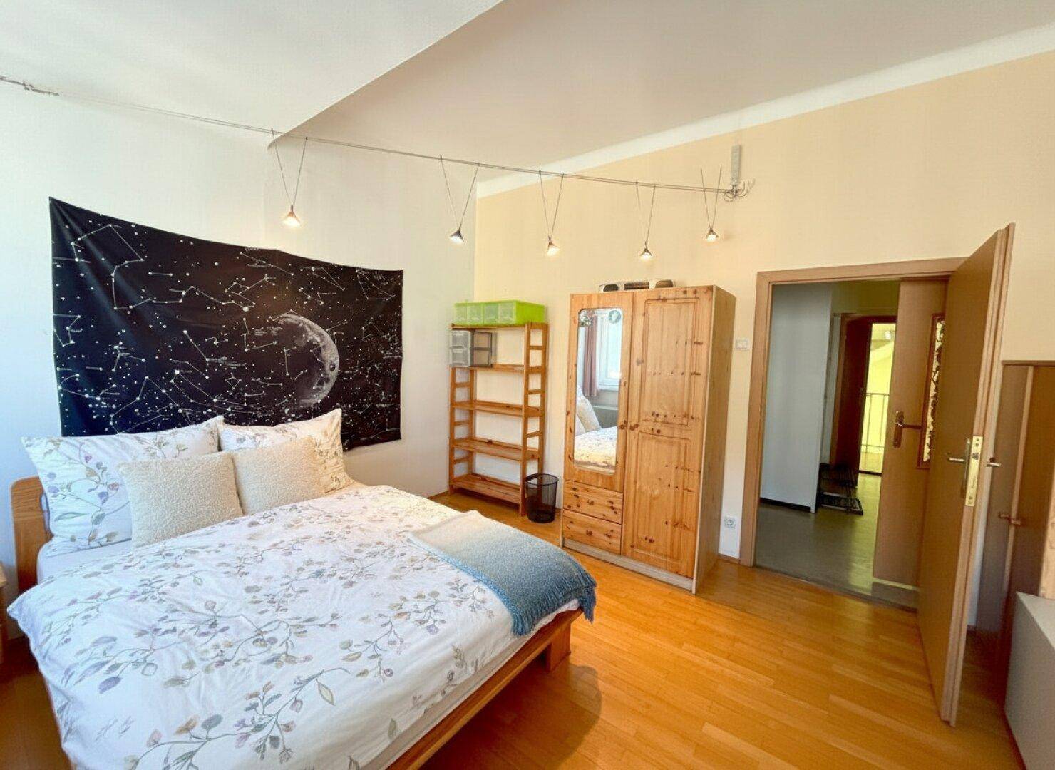 Gemütliches Schlafzimmer mit Holzbett, Kleiderschrank und Blick in den Flur.